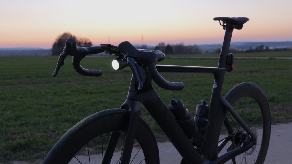 Lupine SL Grano practically tested at twilight on a Canyon Aeroad, mounted below a Garmin front mount on the road bike handlebar