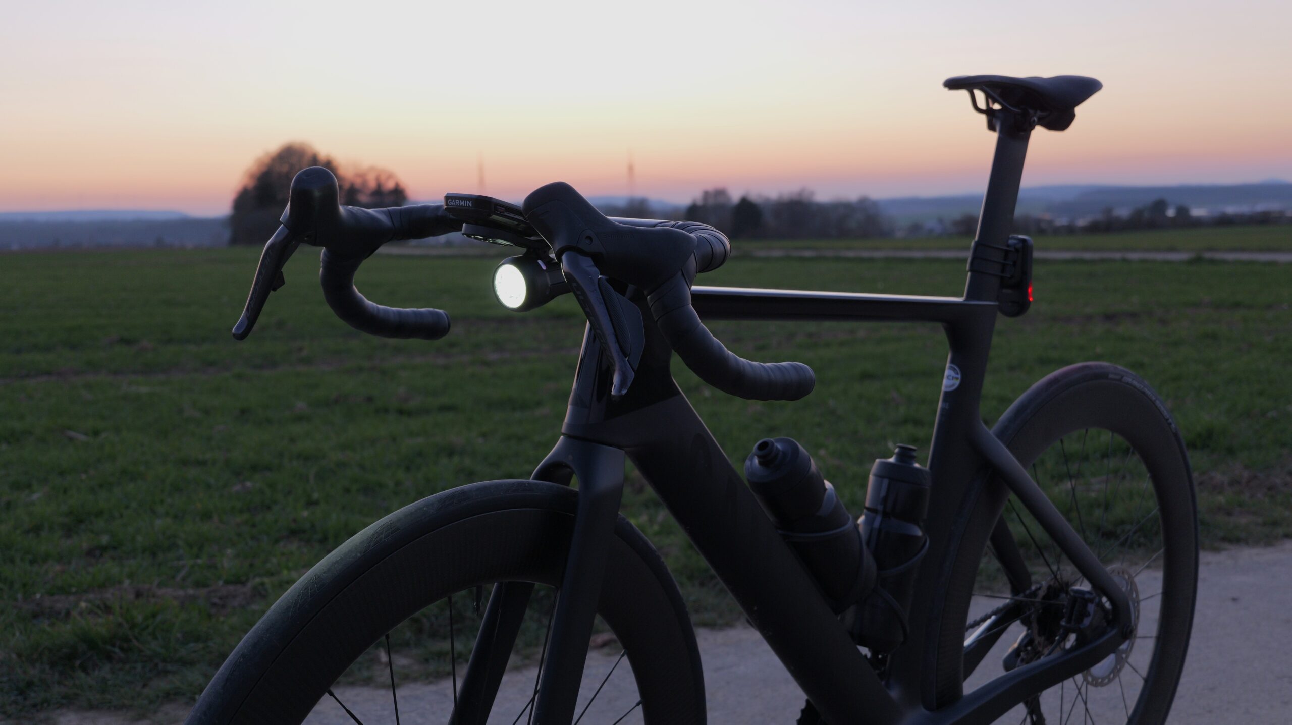 Lupine SL Grano practically tested at twilight on a Canyon Aeroad, mounted below a Garmin front mount on the road bike handlebar