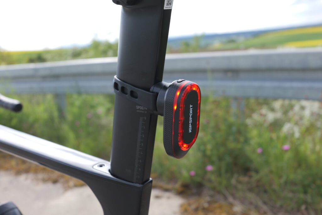 Close-up of an iGPSport SR Mini rear light on a Canyon Aeroad seatpost, fitted with a rubber strap mount.