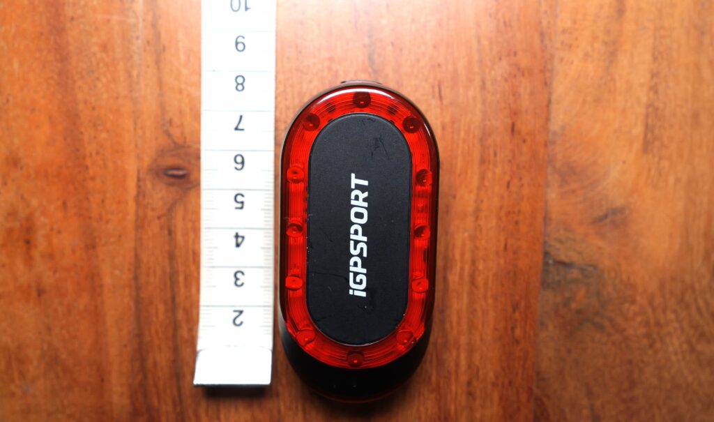 iGPSPORT SR Mini with a tape measure checking case length on a wooden table.