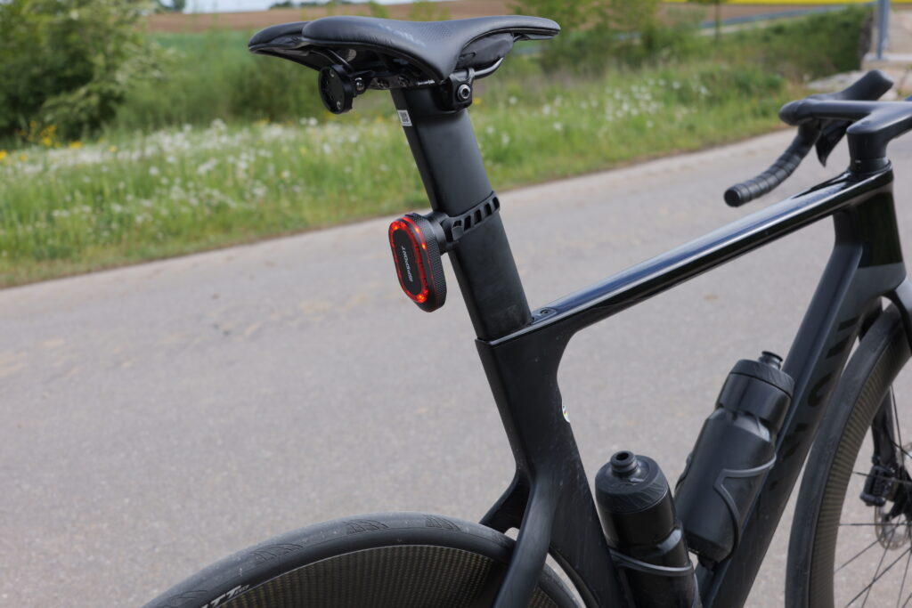 iGPSport SR Mini on a Canyon Aeroad seatpost, side view with the mount visible and rear light switched on.