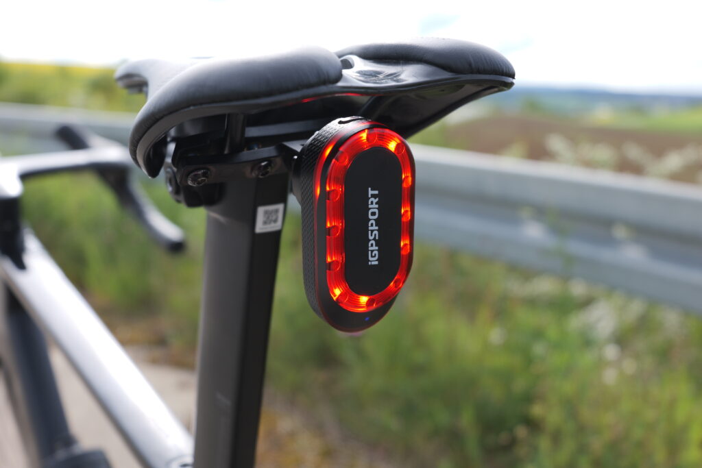 iGPSport SR Mini rear light mounted directly below the saddle on a Canyon Aeroad, with the LED light on.