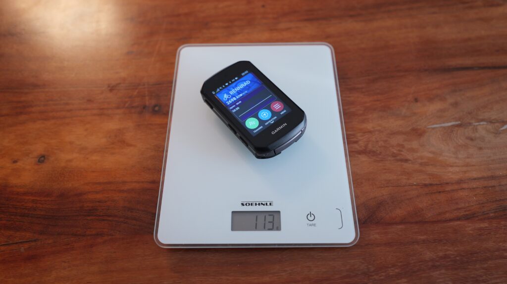 Garmin bike computer on a digital kitchen scale whose display shows a weight of 113 grams.