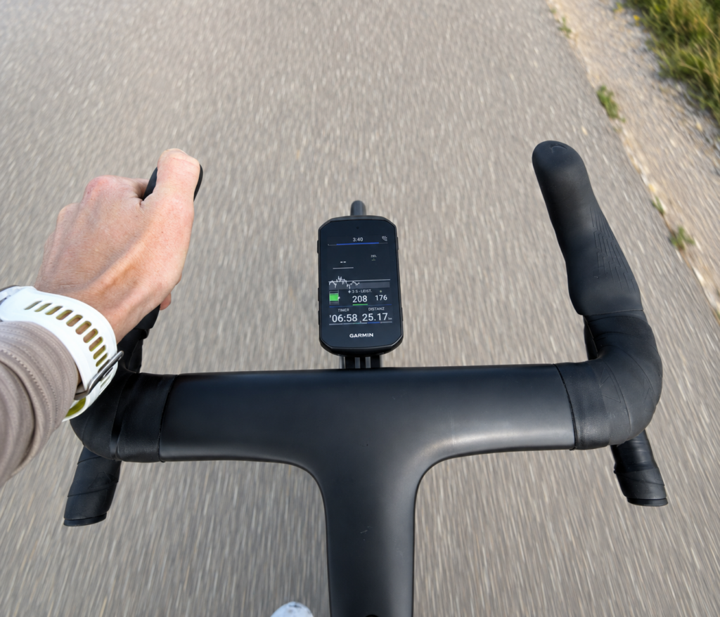 Rider's view of a black road bike handlebar with Garmin Edge 850. The display shows training data during the ride.