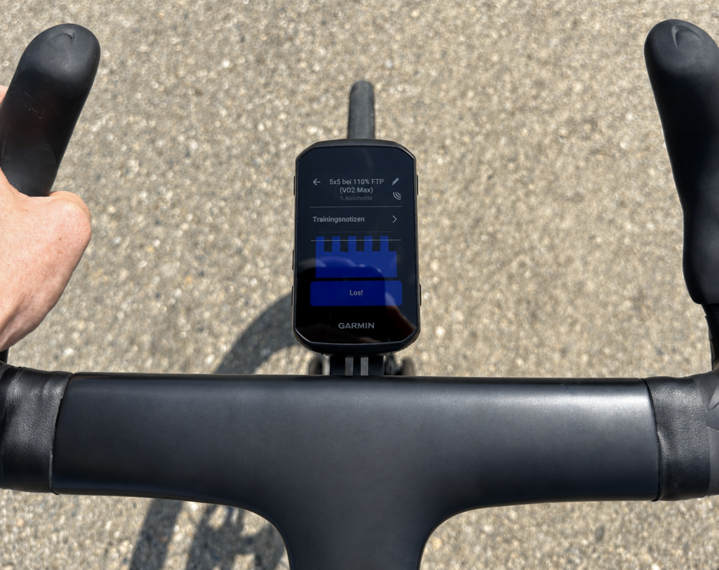 Rider's view of a black bicycle handlebar with Garmin Edge 850. The display shows a VO₂max interval workout with five sections at 110 percent FTP.