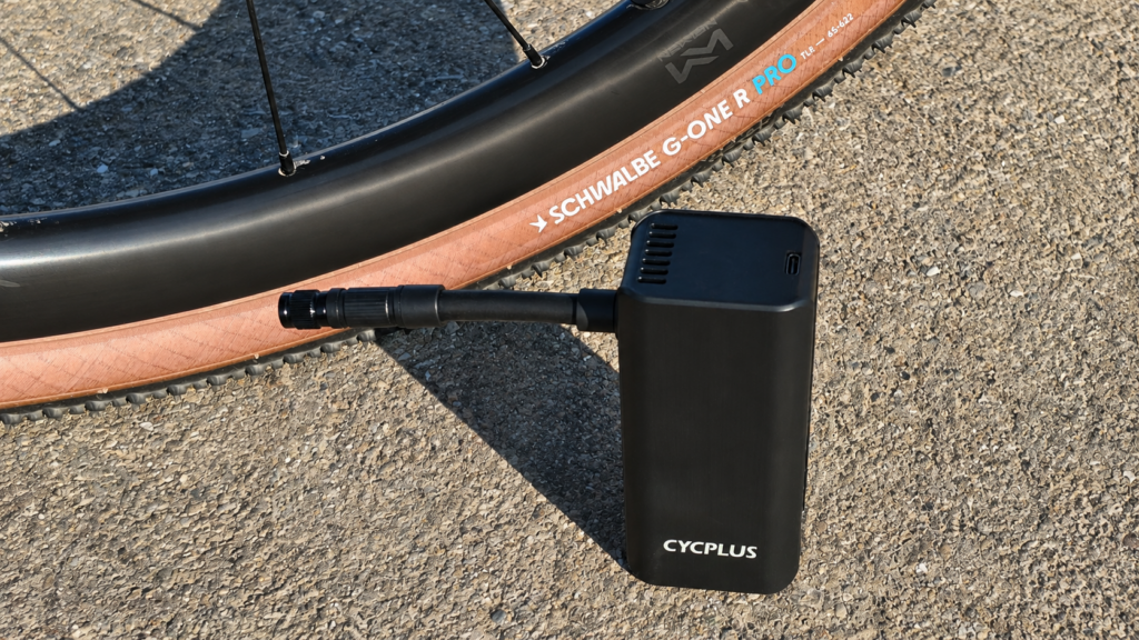 CYCPLUS A3 Mini electric bike pump with air hose beside a Schwalbe G-One R Pro gravel tyre.