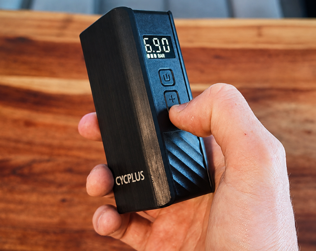 CYCPLUS A3 Mini electric bike pump held in a hand with a digital pressure reading of 6.90 bar.